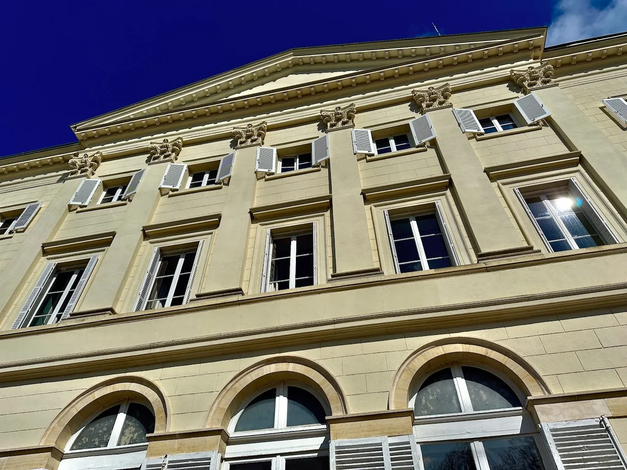 The façade of the château on HEC Paris’s campus at Jouy-en-Josas, its shutters open, photographed from below against a deep blue sky.