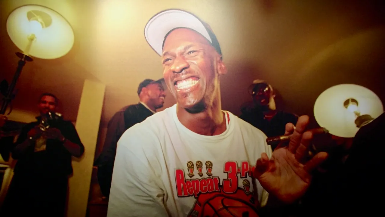 A printed photograph of Michael Jordan laughing in a locker room, wearing a Repeat 3-Peat T-shirt and holding a cigar.